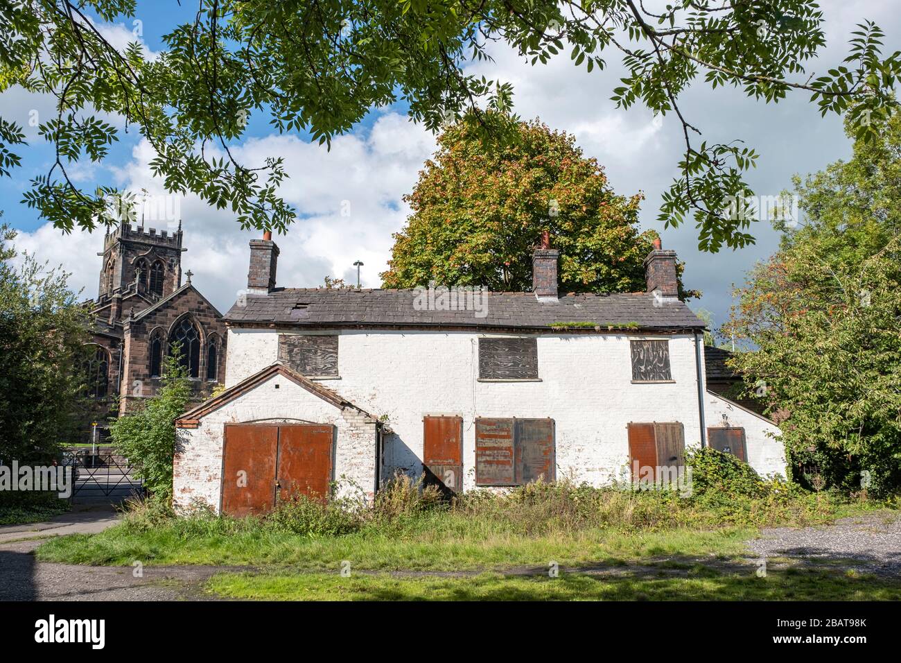 Derelict Canal Wharf Cottage with St Michael and All Angels church in Middlewich Cheshire UK Stock Photo