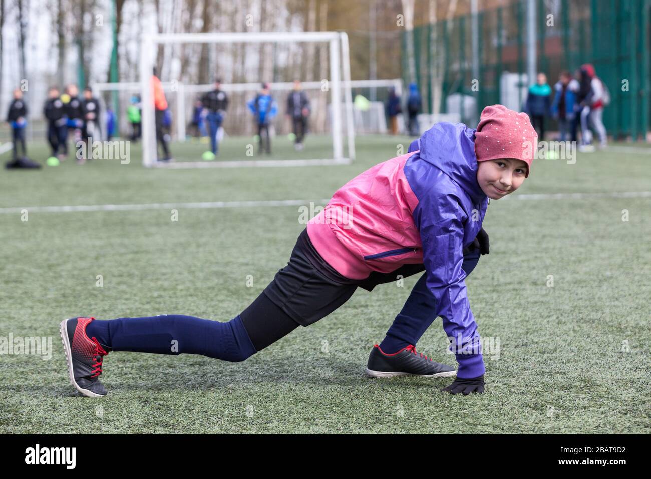 Elevenyear female football player does exercises for flexibility, warmup before match Stock