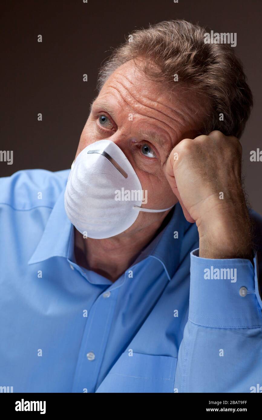 Worried senior man with surgical mask stays at home because of  quarantine of covid-19 Stock Photo