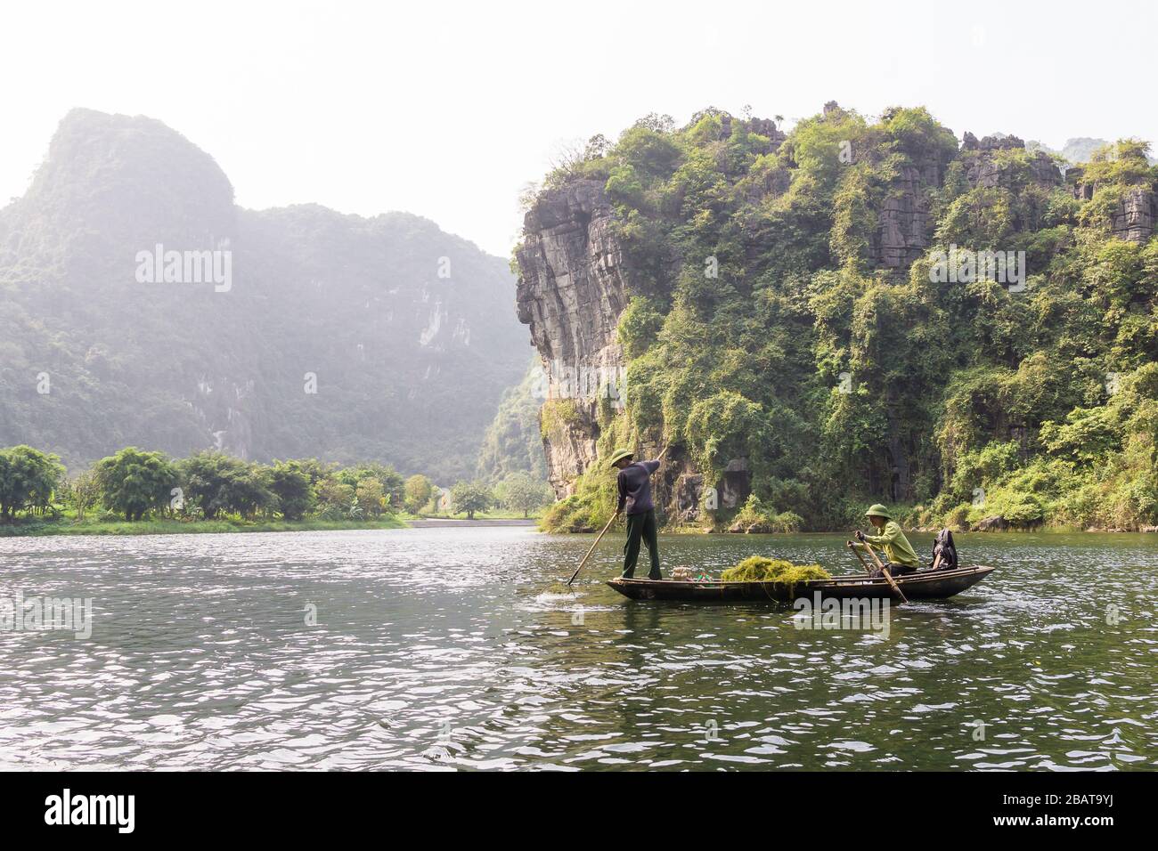 Vietnam Trang An Landscape - Two Vietnamese men in rowboat in the Red River Delta in Ninh Binh Province of North Vietnam, Southeast Asia. Stock Photo