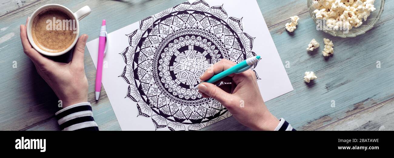 Adult coloring book, stress relieving trend. Art therapy, mental health, creativity and mindfulness concept. Flat lay close up on woman hands coloring Stock Photo