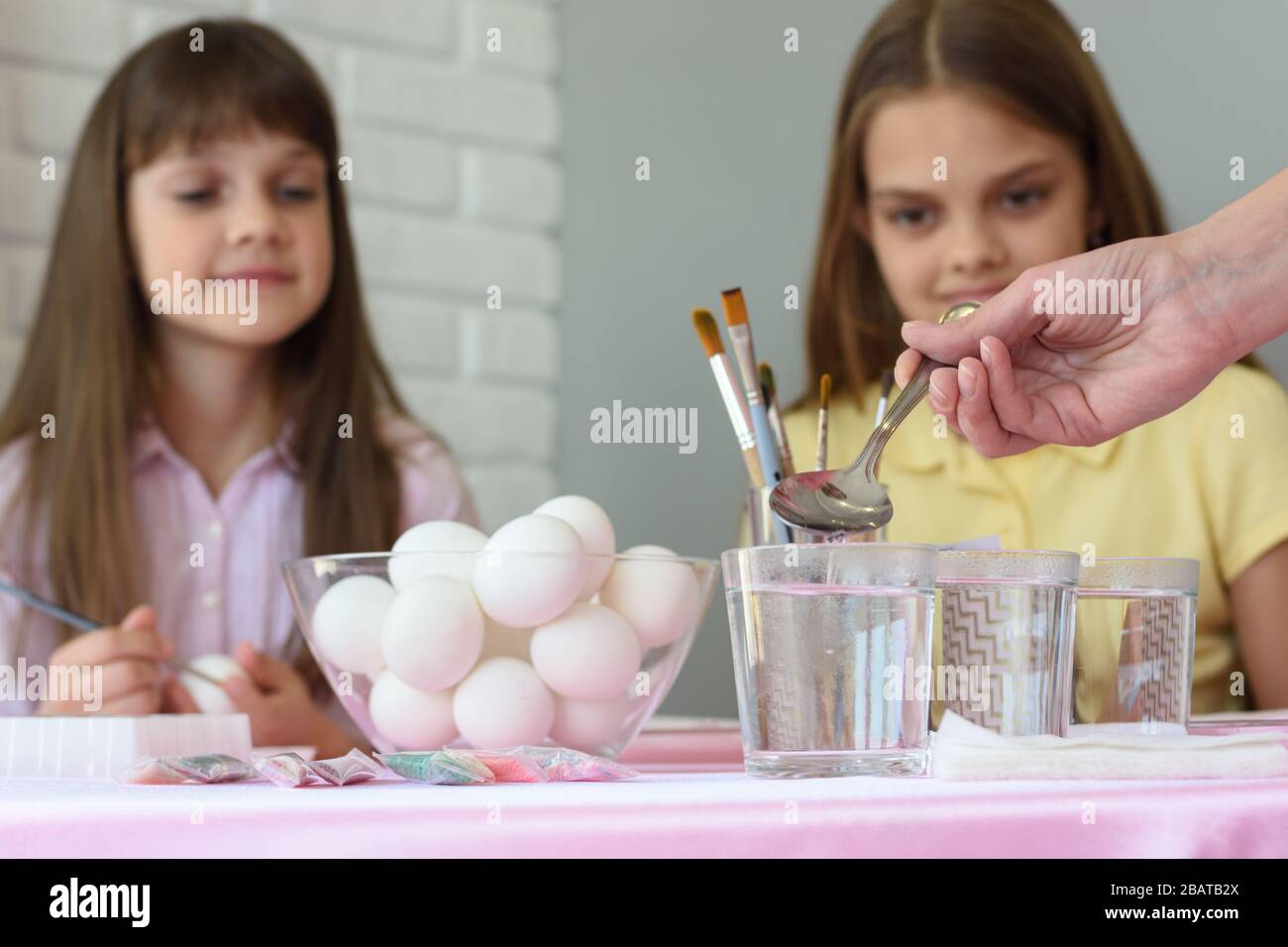 Mom pours vinegar in glasses of water for coloring eggs for Easter ...