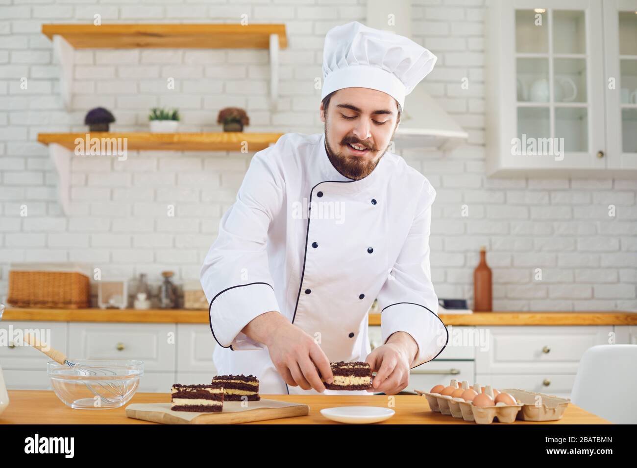 A male pastry chef works decorating a cake on a kitchen bakery Stock Photo