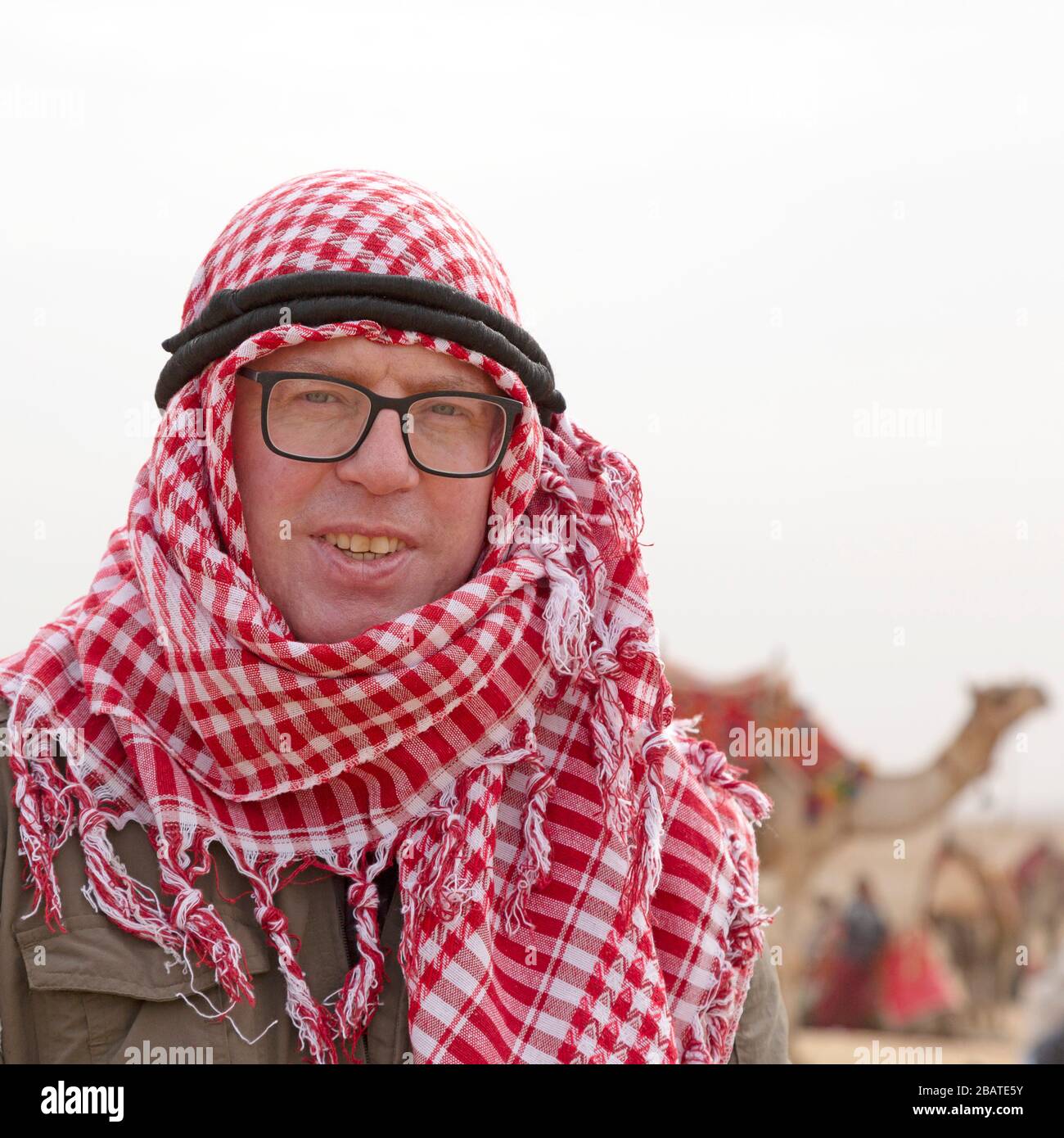 A tourist wearing a traditional Middle-Eastern headdress while visiting the Giza Plateau at Cairo, Egypt. Stock Photo