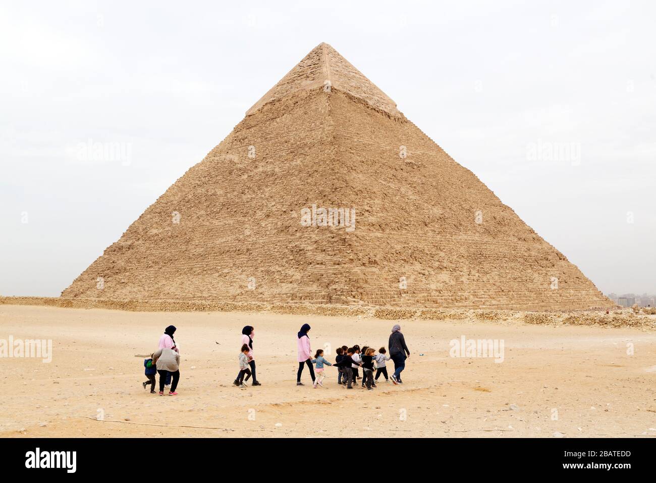 A group of people walks by the Pyramid of Khufu, also known as the Pyramid of Cheops, on the Giza Plateau at Cairo, Egypt. Stock Photo