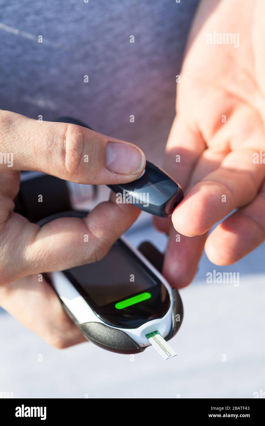 Man Using Glucometer Diabetes checking blood sugar level. Man using lancelet and glucometer ...