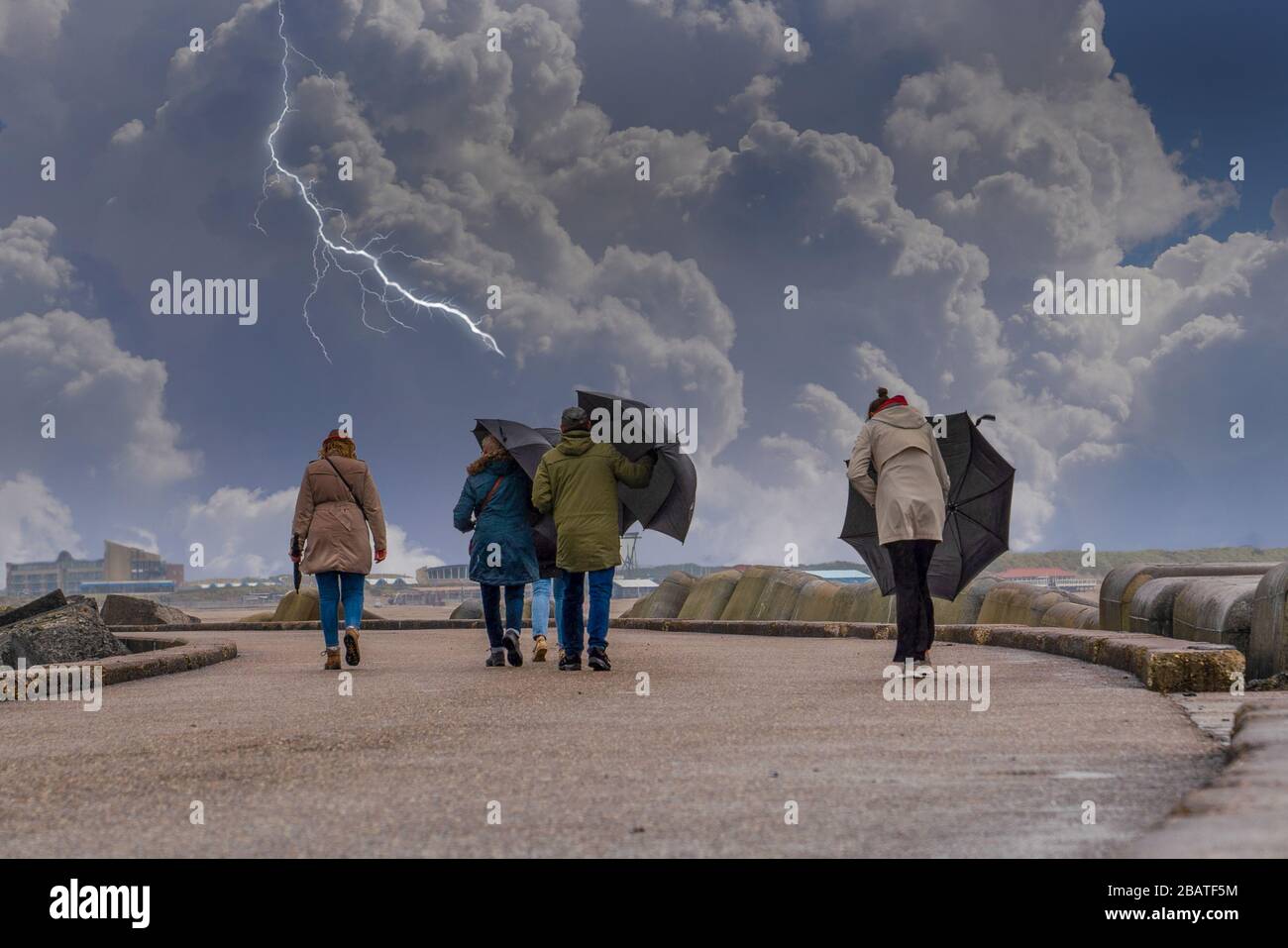 A group of people walking and trying to keep umbrellas in a windy day