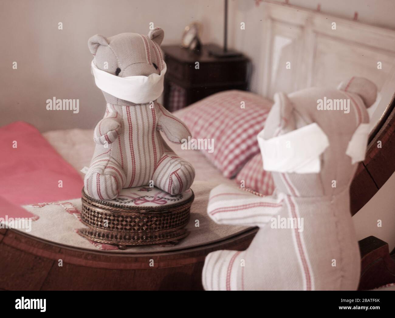 Teddy bear wearing a mask and looking at himself in a mirror Stock