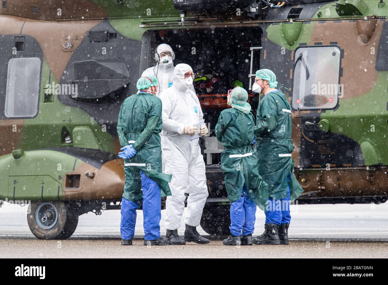 29 March 2020, North Rhine-Westphalia, Mülheim an der Ruhr: Rescue workers in protective clothing stand in front of a military helicopter at the airport. Previously, two patients were brought from Metz in France to Mühlheim to be treated at the university hospital in Essen. Photo: Marcel Kusch/dpa Stock Photo