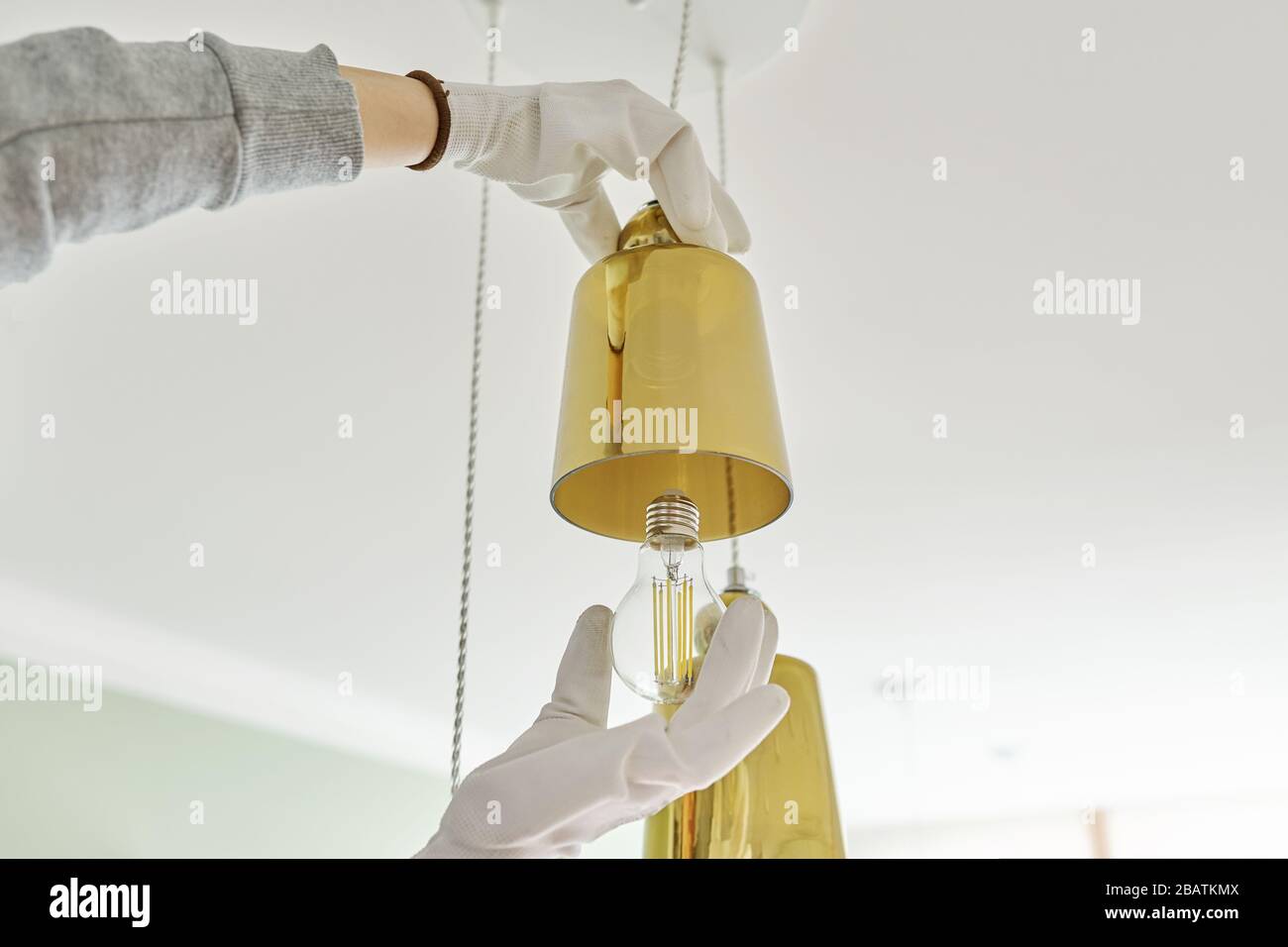 Hands installing LED bulb in lamp, chandelier. Stock Photo