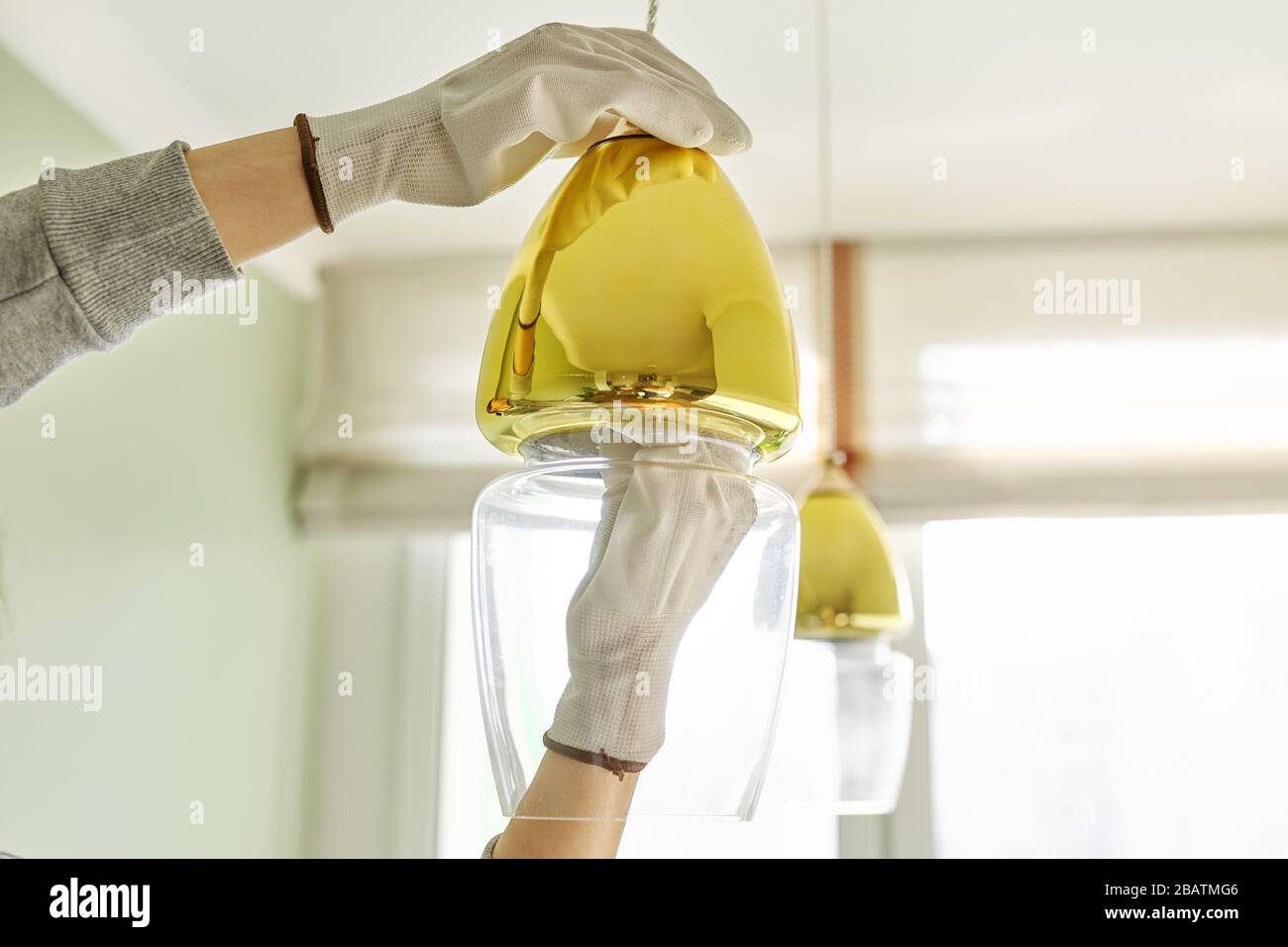 Hands installing LED bulb in lamp, chandelier. Stock Photo