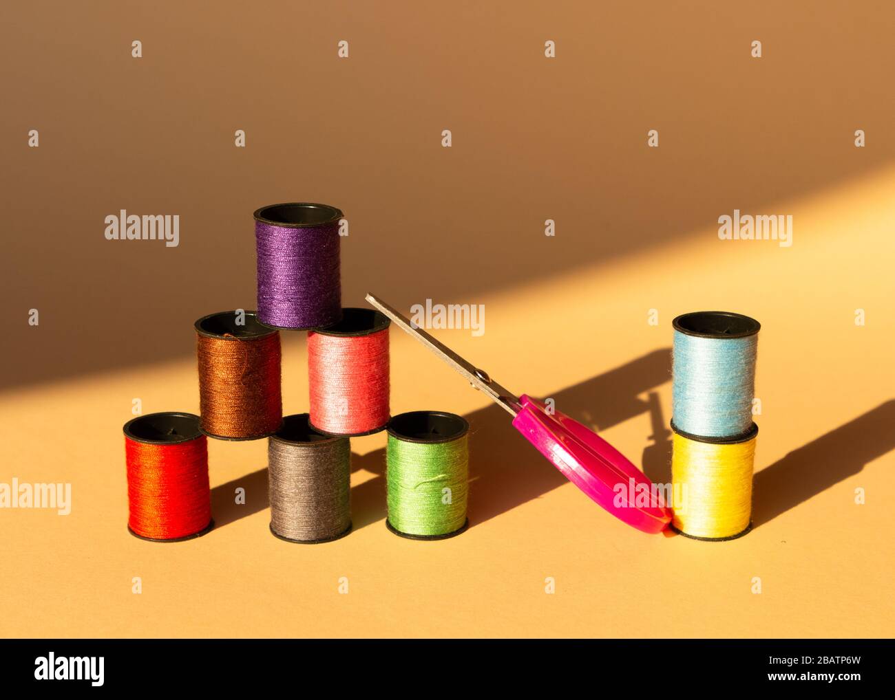 Creative composition with spools of colored threads and scissors. Sewing accessories, tailoring set. Stock Photo