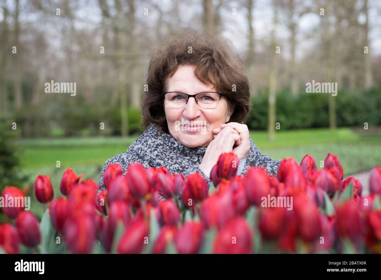 A smiling retired woman is enjoying flower fields in Holland Stock Photo