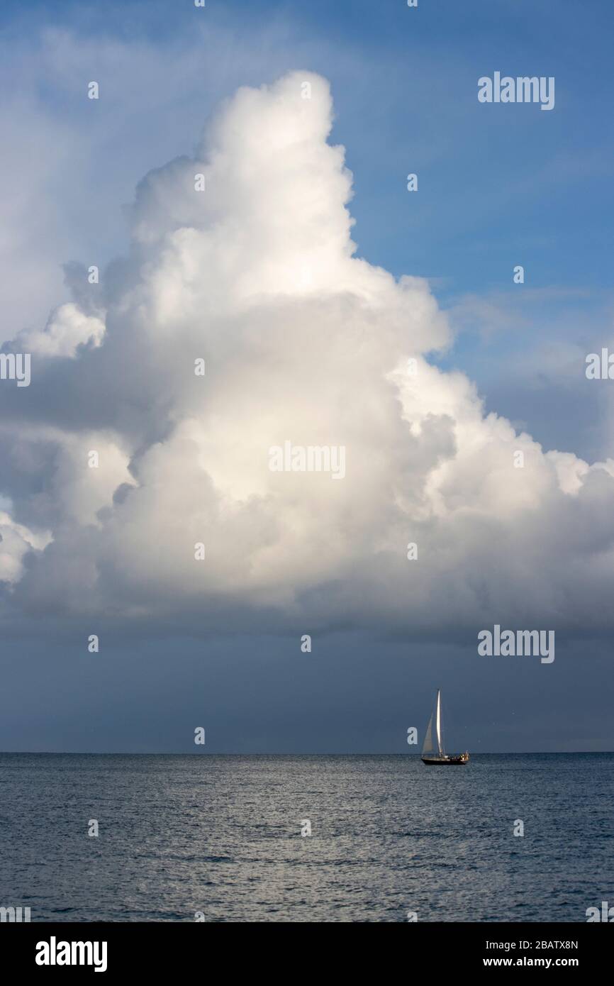 A yachts' sail mimics the cumulonimbus cloud forming triangles Stock Photo