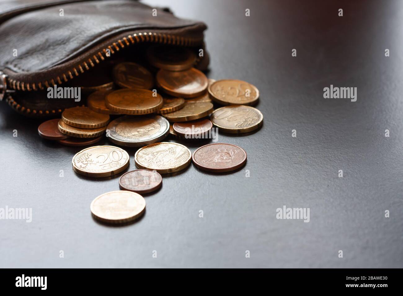 Leather wallet with some euro coins on black background, money saving concept. Place for text