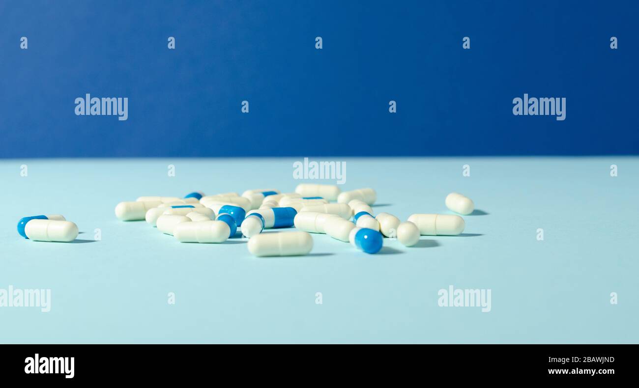 Medicines white and blue capsules on the blue background with copy space. Antibiotic. Pharmacy template. Pharmaceutical medicament. Stock Photo