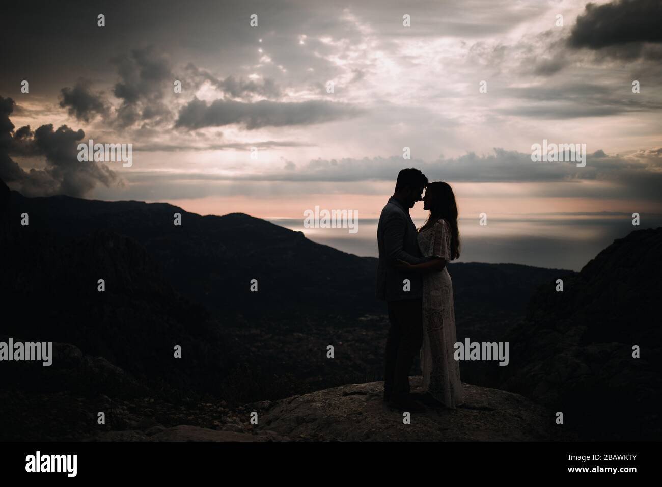 couple standing on the top of mountain, holding hands and watching ...