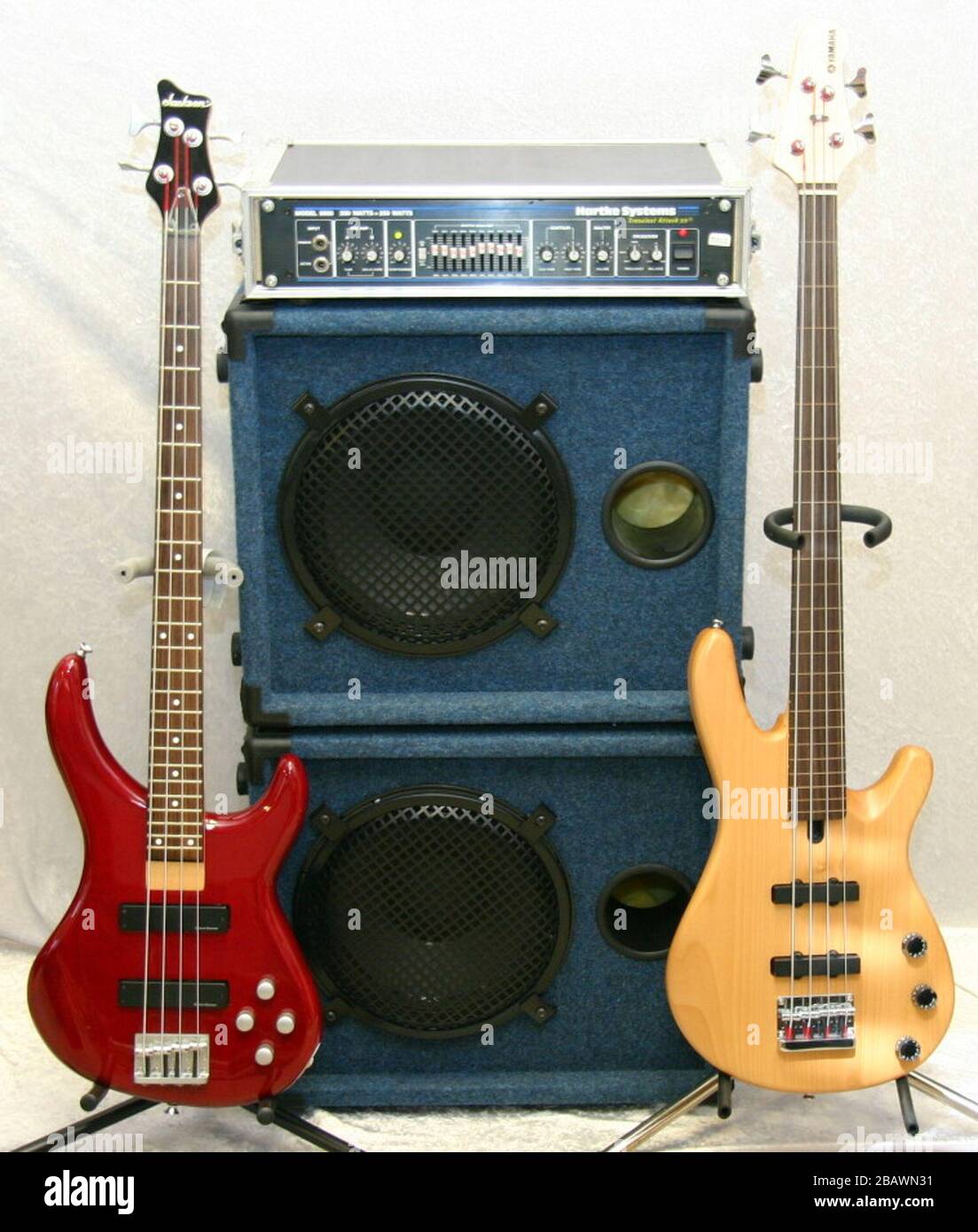 English: The red bass guitar to the left is a Jackson C4A, with 2 active  humbucker pickups. The natural finish one to the right is a Yamaha BB404F  Fretless with fret lines.