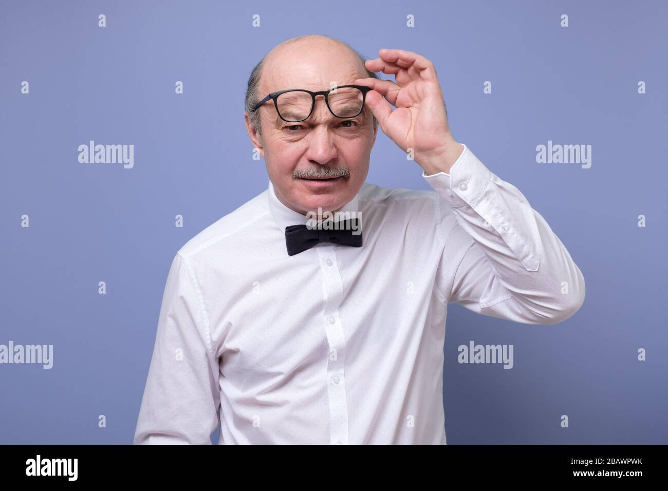 Amazed senior man looking at camera through glasses having some doubts Stock Photo
