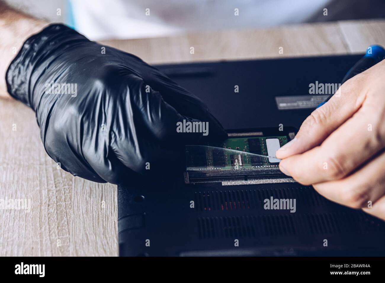Technician installing new RAM module into the memory slot Stock Photo