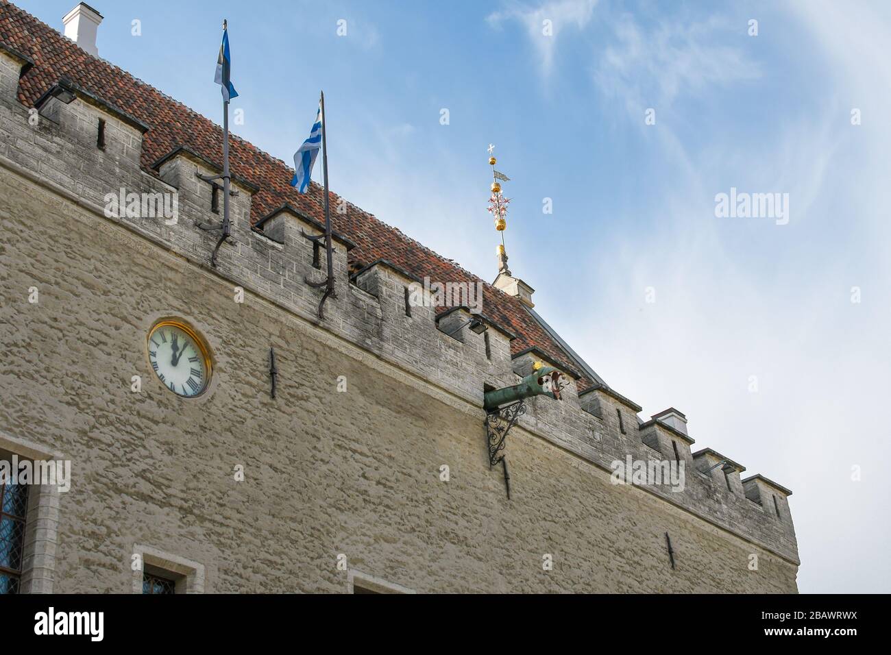 One of the dragon head gargoyles protrudes near the clock on the medieval Town Hall building in Tallinn Estonia. Stock Photo