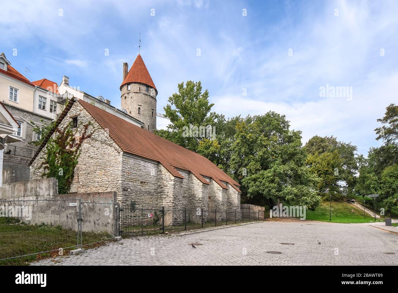 A medieval building sits under the city wall with the Nun's Tower visible above in Tallinn Estonia. Stock Photo