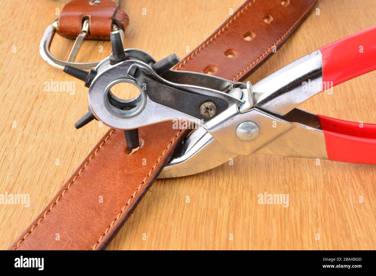 Leather punch tool and leather belth on wooden background in working position Stock Photo