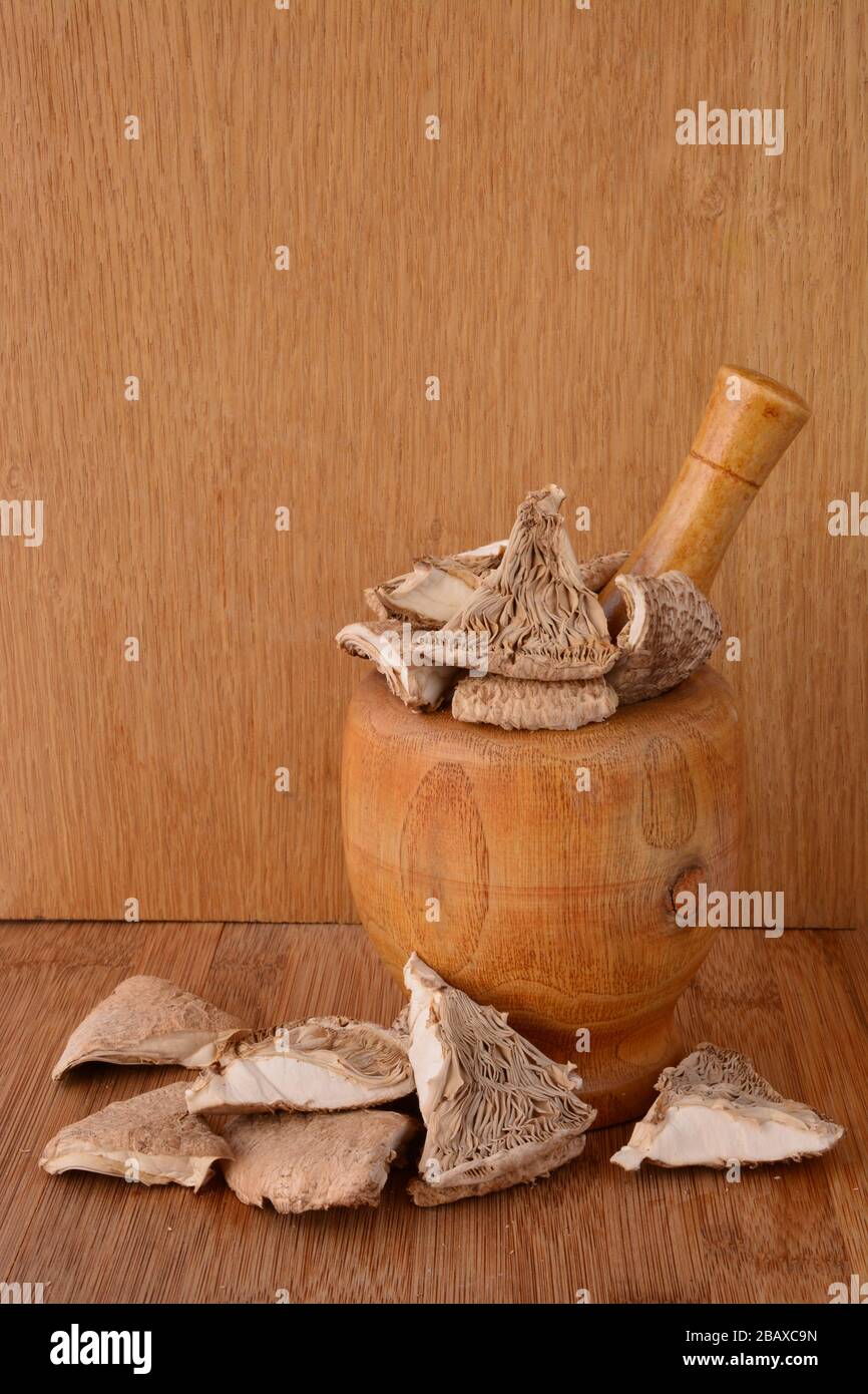 Dry Parasol mushroom or Macrolepiota procera in bamboo  mortar over wooden background, ready for the kitchen Stock Photo