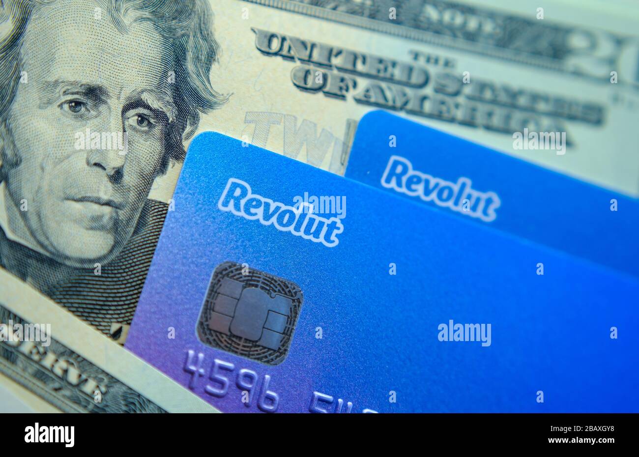 Stone / United Kingdom - March 29 2020: Revolut cards placed on top of dollar notes. Concept photo for revolut bank expansion to American market. Stock Photo