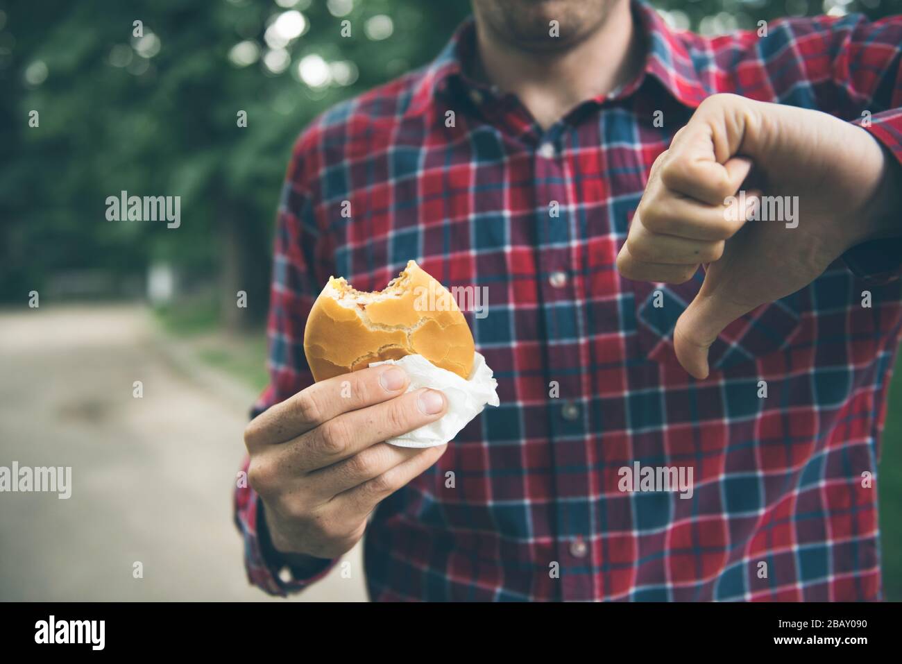 Man opening a hamburger. Man is eating in the park Stock Photo