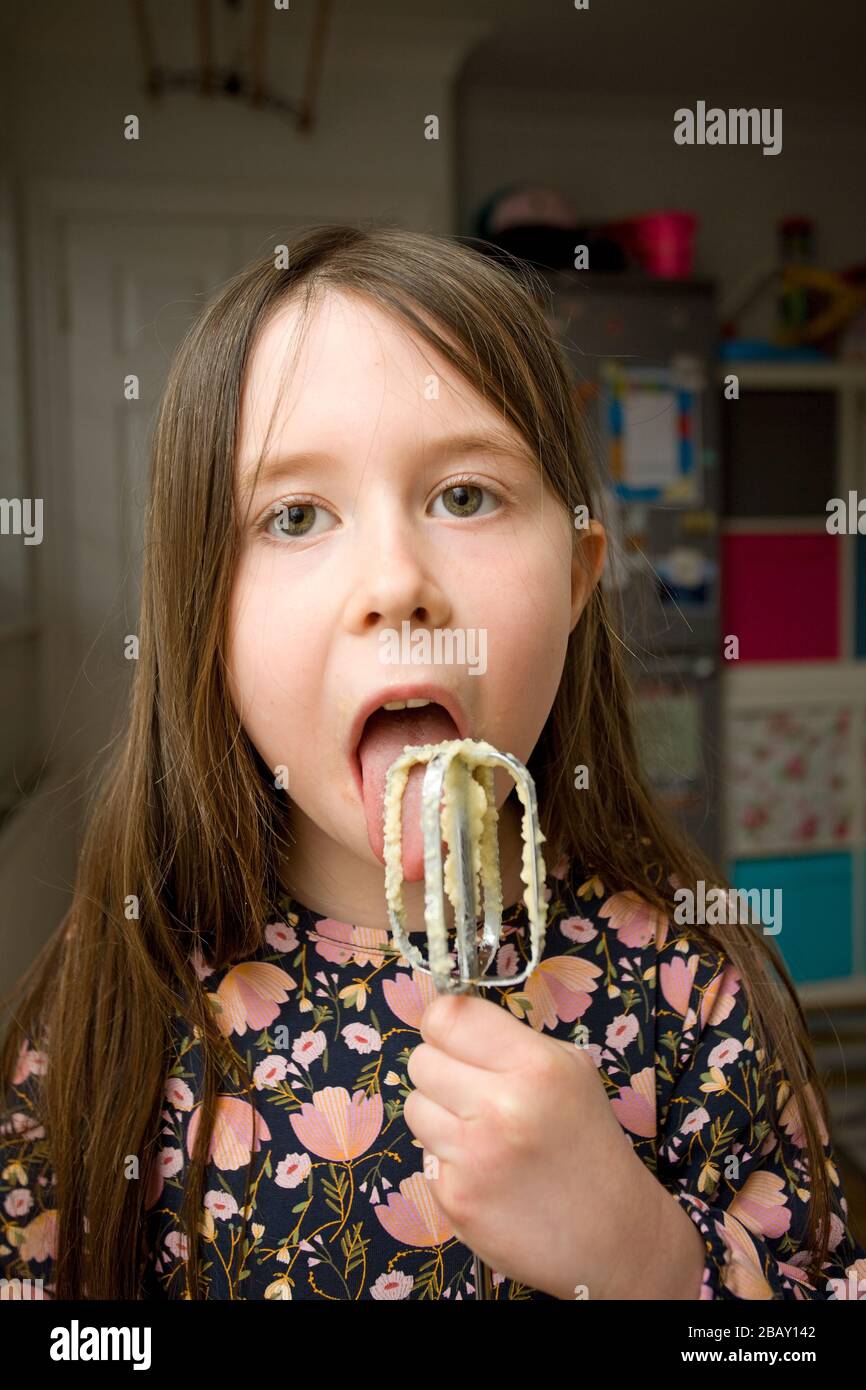 Young girl licking the food mixer paddle Stock Photo