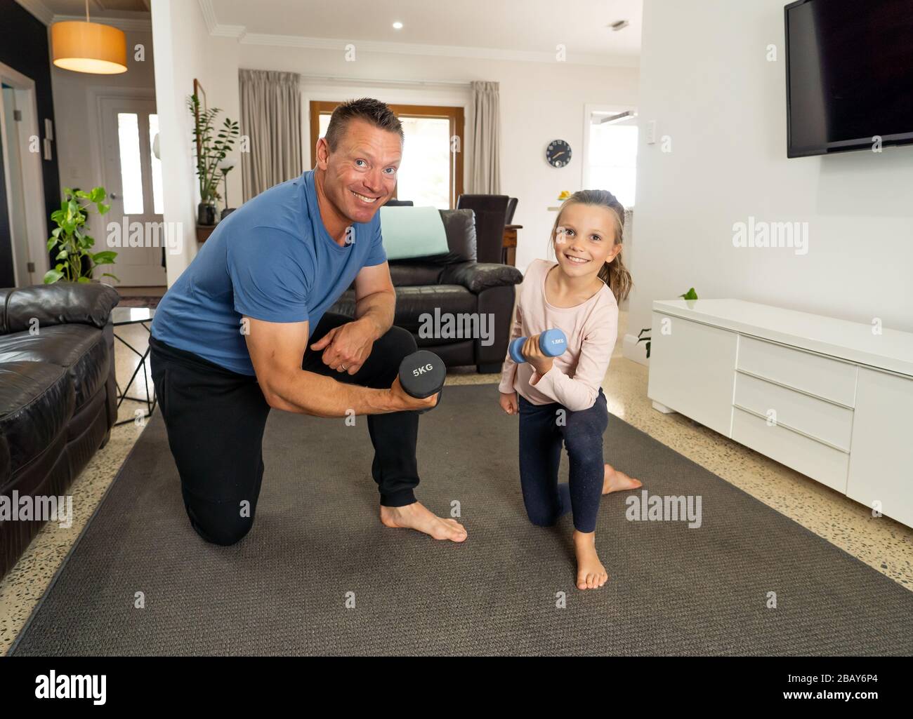 COVID-19 shutdown. Father and daughter in quarantine exercising together with dumbbells. Benefits of physical activity during lockdown. Stay at home, Stock Photo