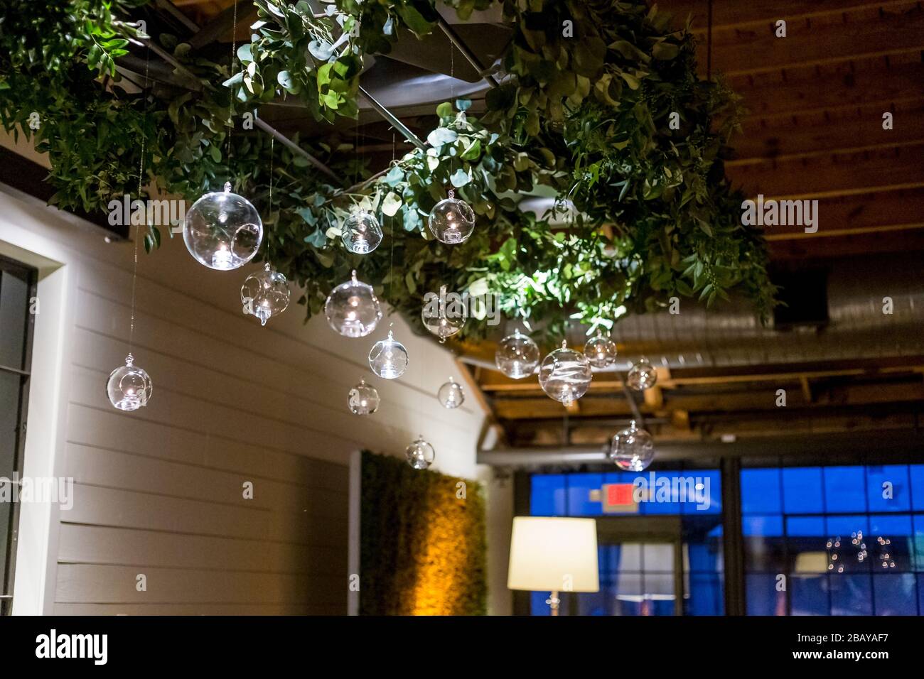 Low angle shot of round glass chandeliers hanging from the floral ceiling Stock Photo
