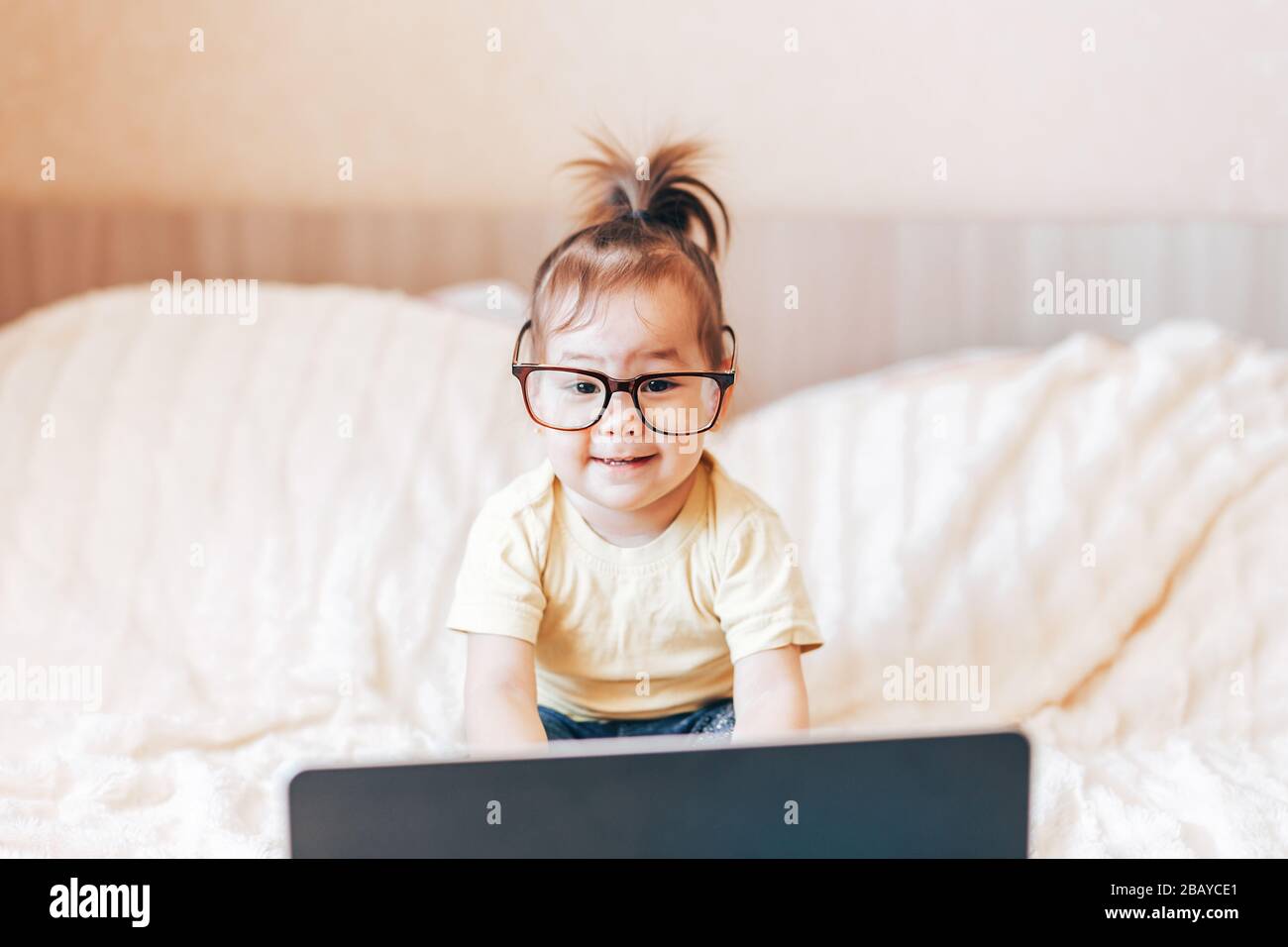 Little happy funny black-haired girl using laptop Stock Photo