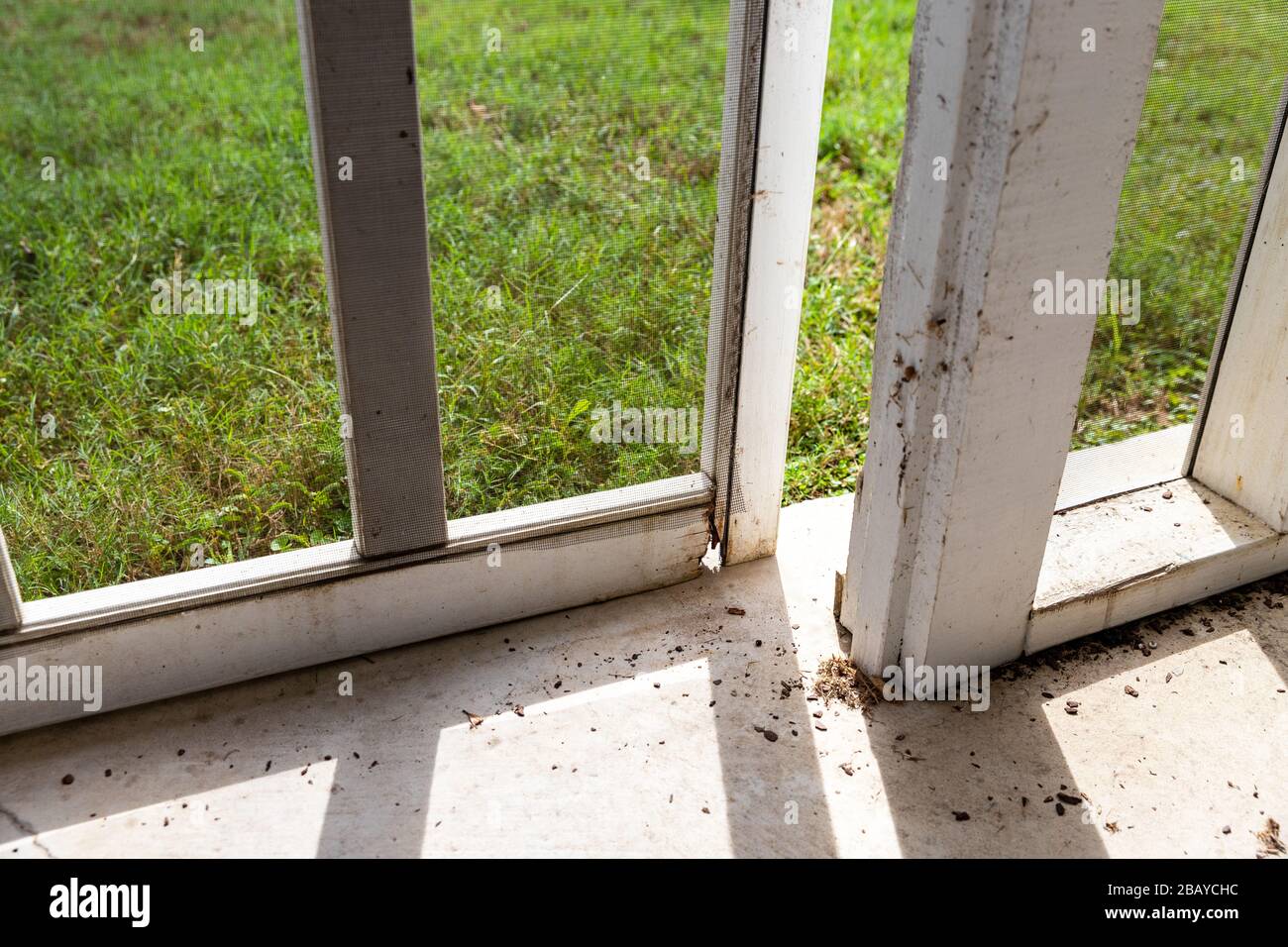 Wooden screen door on back porch with rotten wood Stock Photo