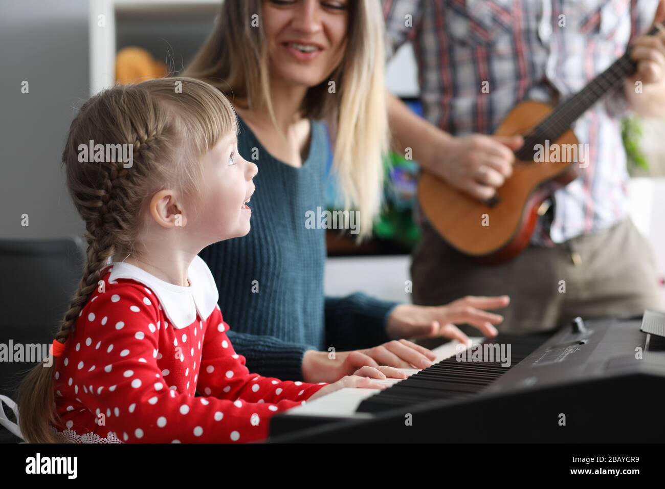 Parents teach daughter to play musical instruments Stock Photo