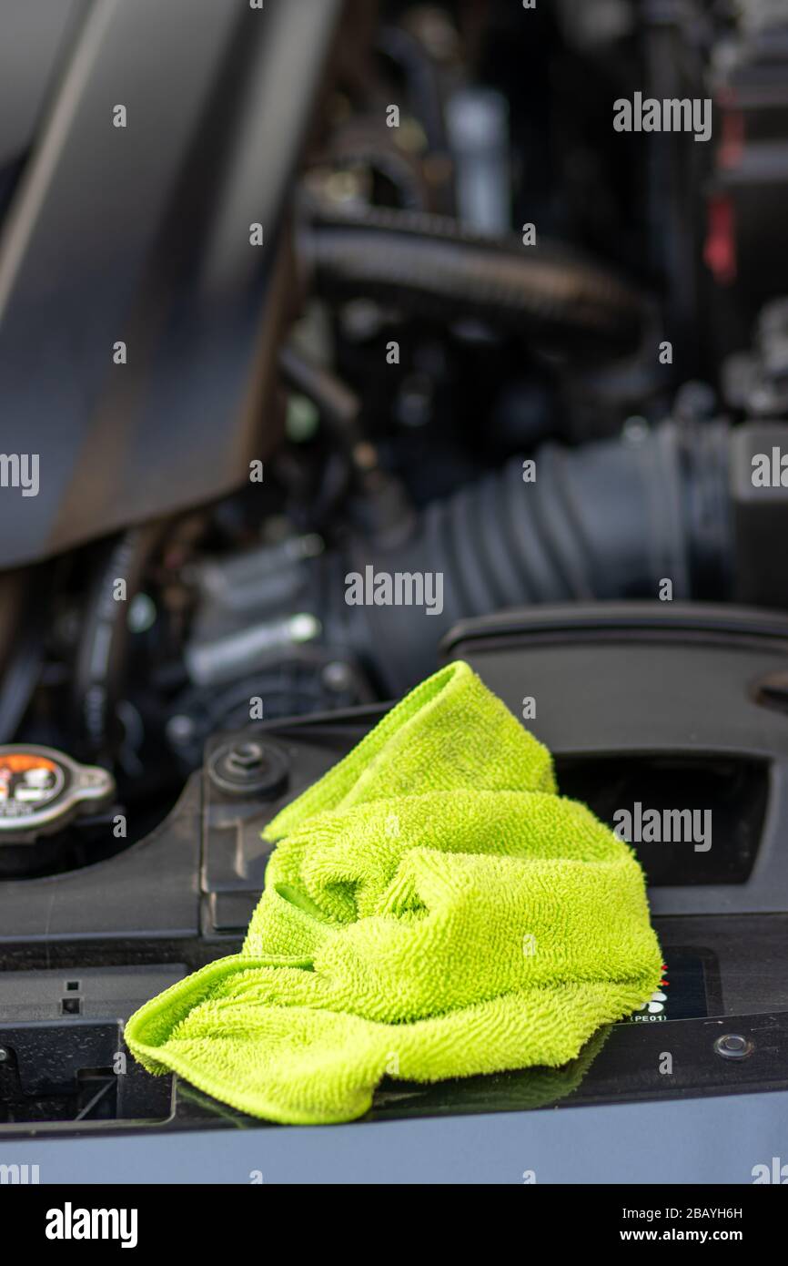 A microfiber cloth lying beside engine of car, close up view. Stock Photo
