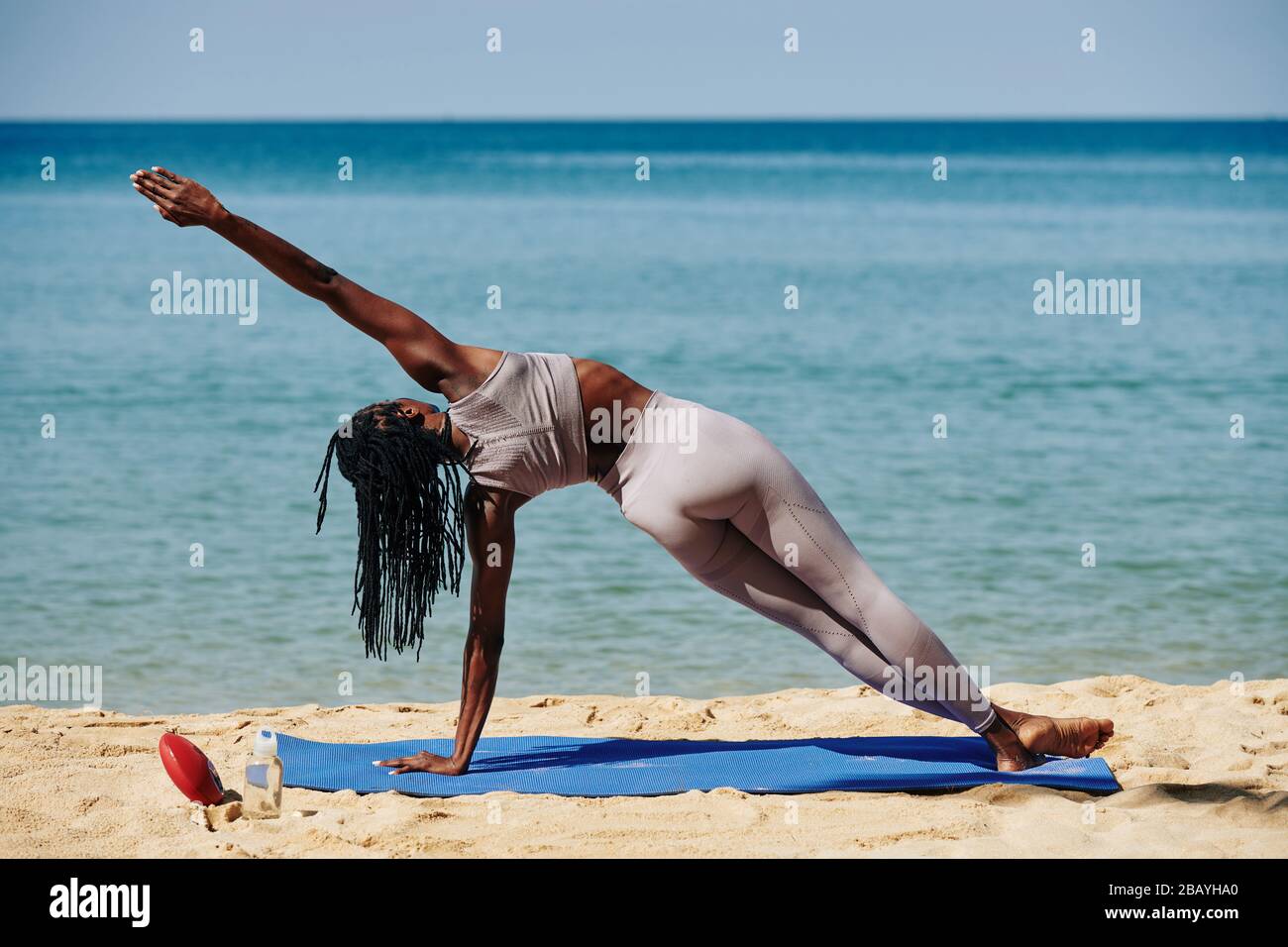 Fit Black young woman doing extended side plank on yoga mat on the