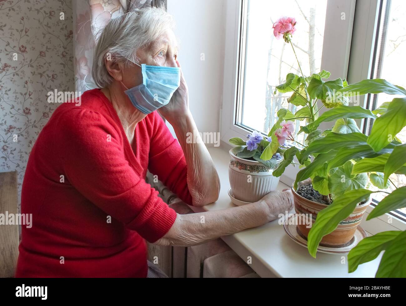 The Covid-19, health, safety and pandemic concept - senior old lonely woman sitting near the window Stock Photo