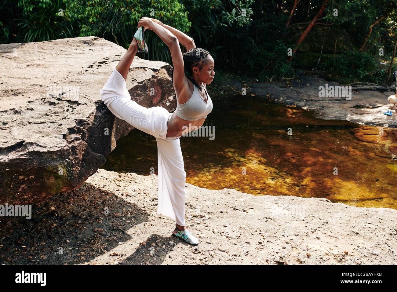 Serious young yogi doing stretching exercise when enjoying getaway Stock Photo