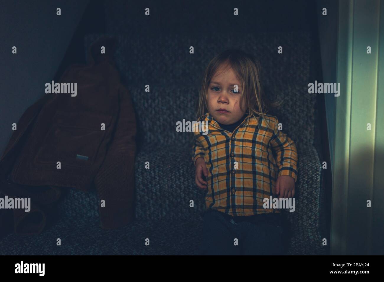 A little preschooler is relaxing on the stairs at home Stock Photo