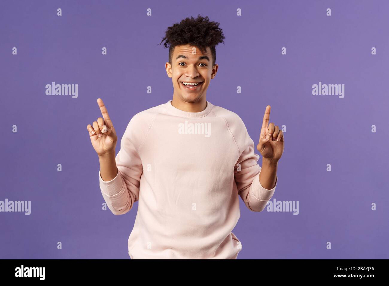 Portrait of charismatic lively young man heard about good deal, asking question intrigued, pointing fingers up, smiling upbeat at camera, look with Stock Photo