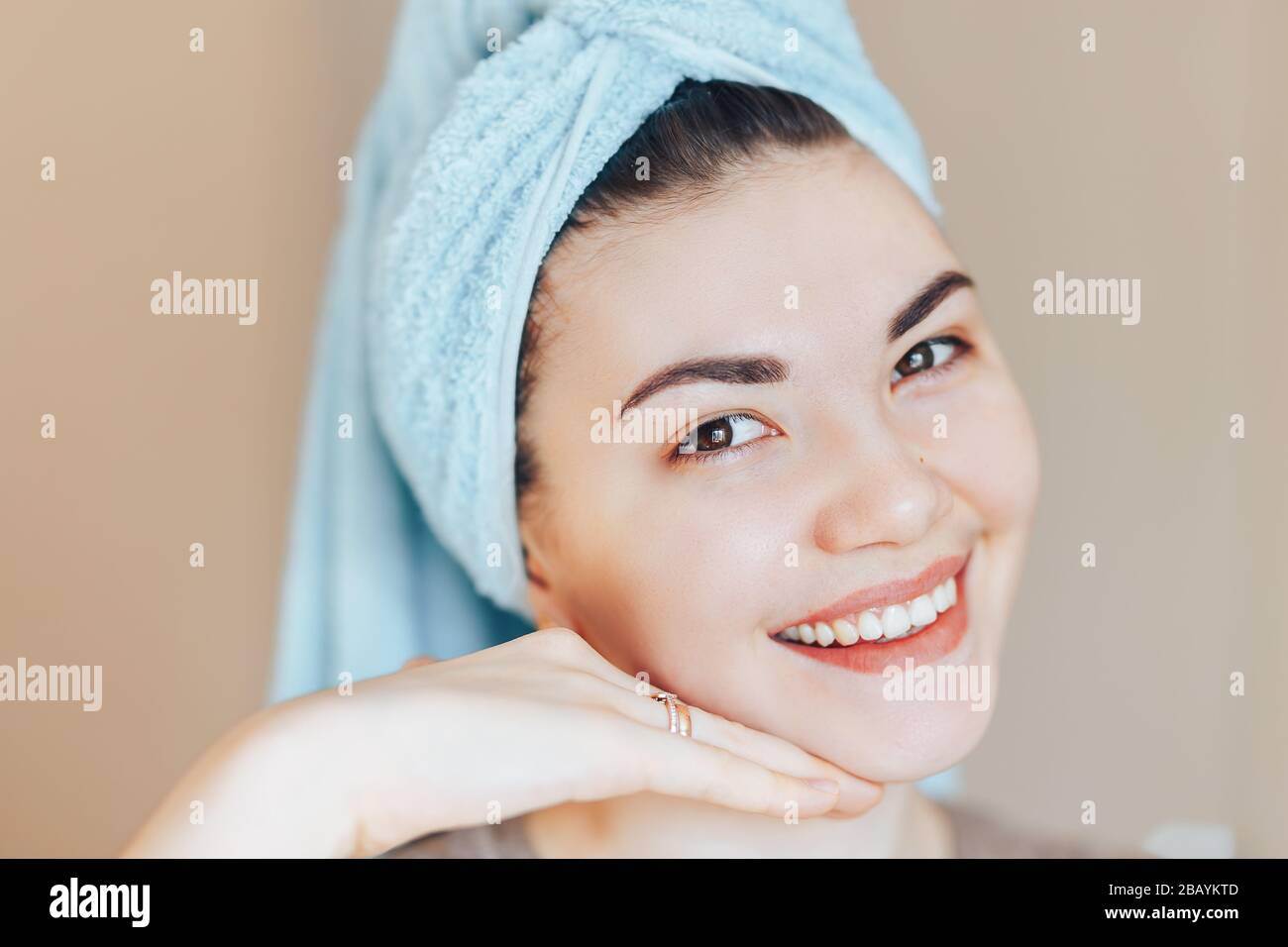 Close up shot of glad satisfied woman being happy after spa procedure, has fresh soft healthy skin, broad smile, white perfect teeth touch her face Stock Photo