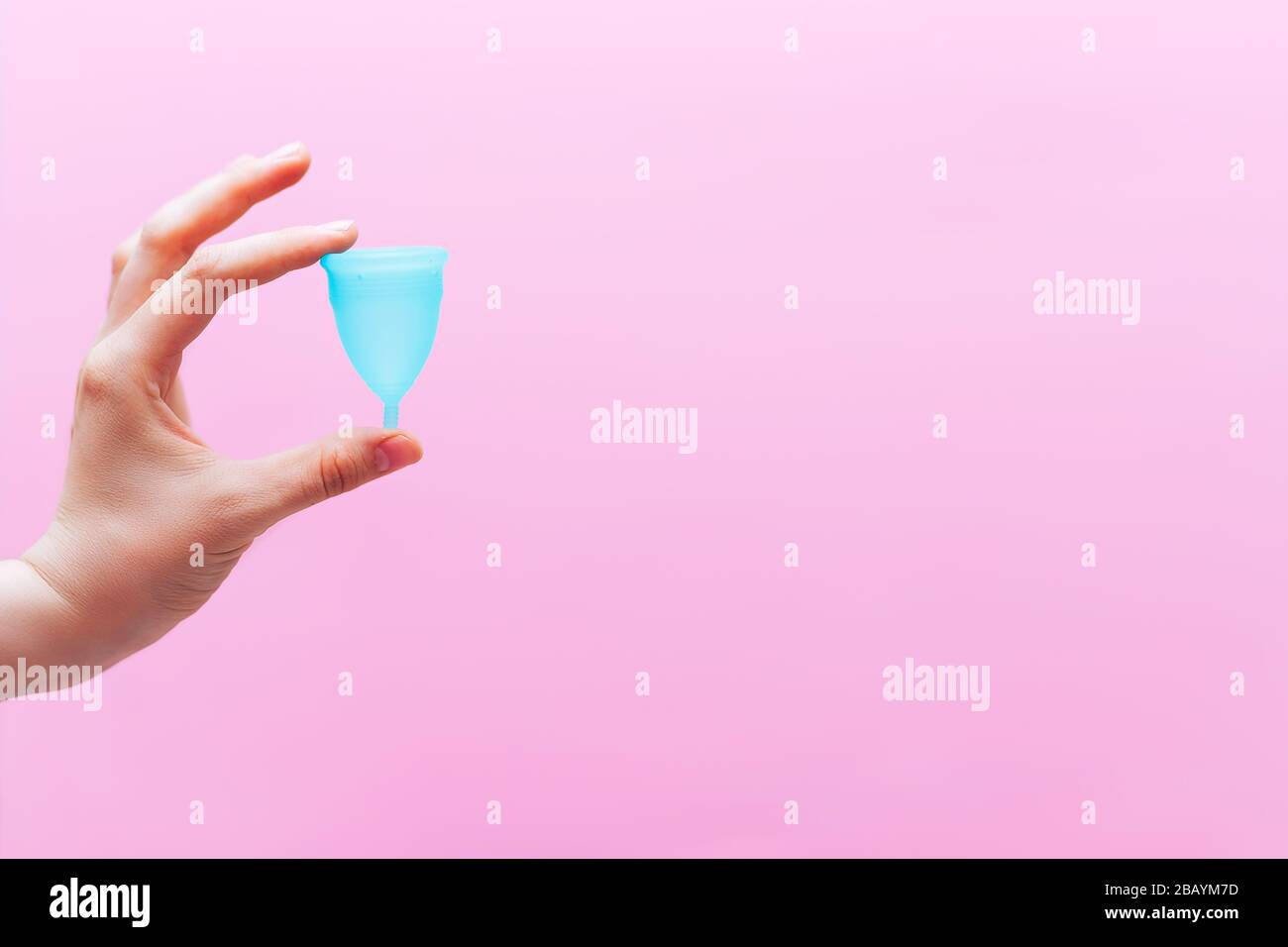 Close up of woman hand holding menstrual cup over pink background. Women health concept, zero waste alternatives Stock Photo