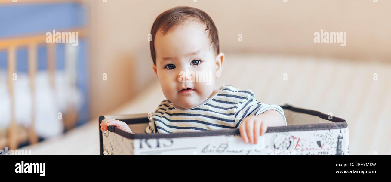 pretty baby infant boy or girl sitting inside a box in apartment Stock
