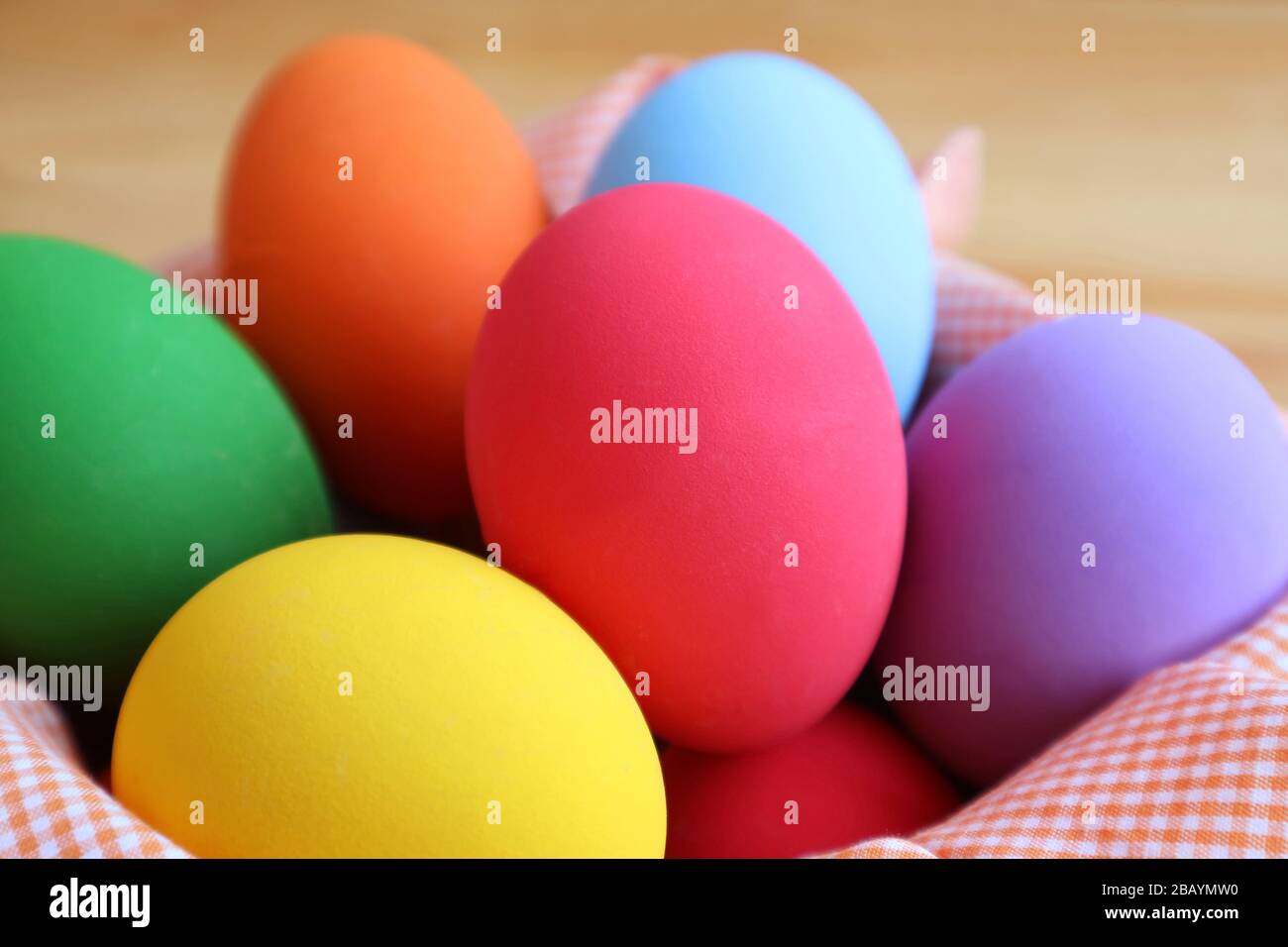 Closeup Multi-colored Easter Eggs in a Basket on Wooden Background Stock Photo