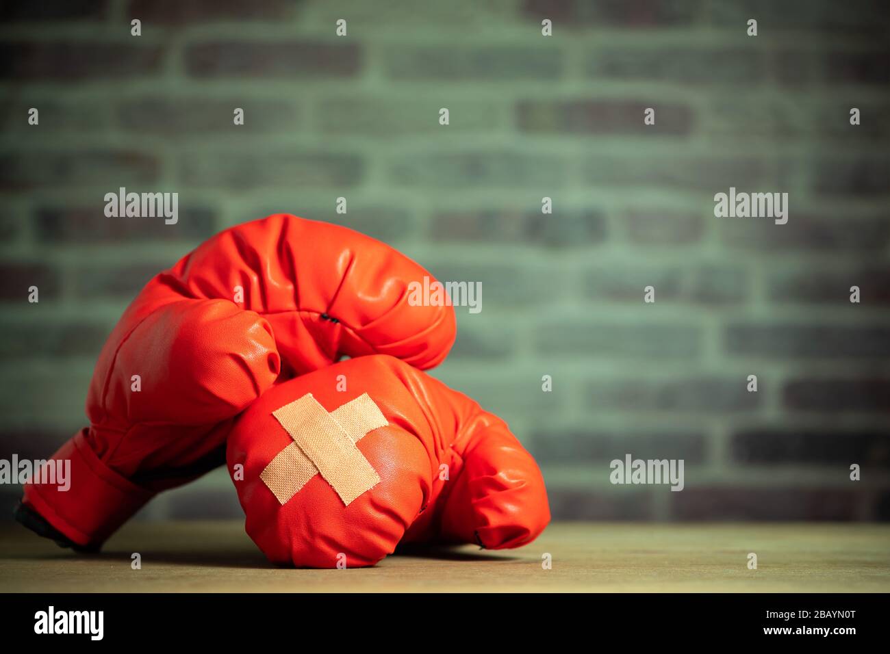 Red boxing gloves on wooden table and brick wall at the sport gym