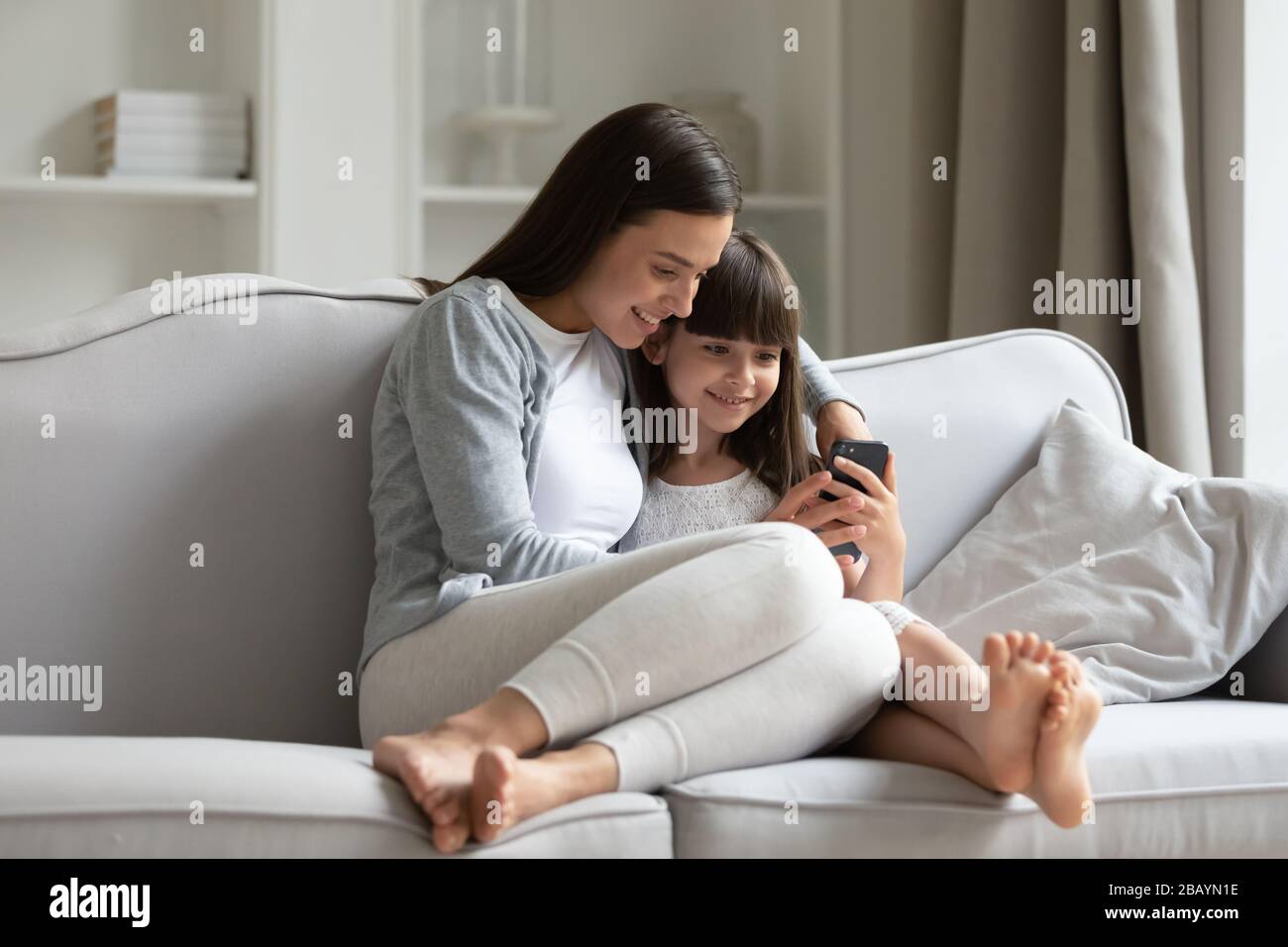 Young mother and little daughter have fun using smartphone Stock Photo ...