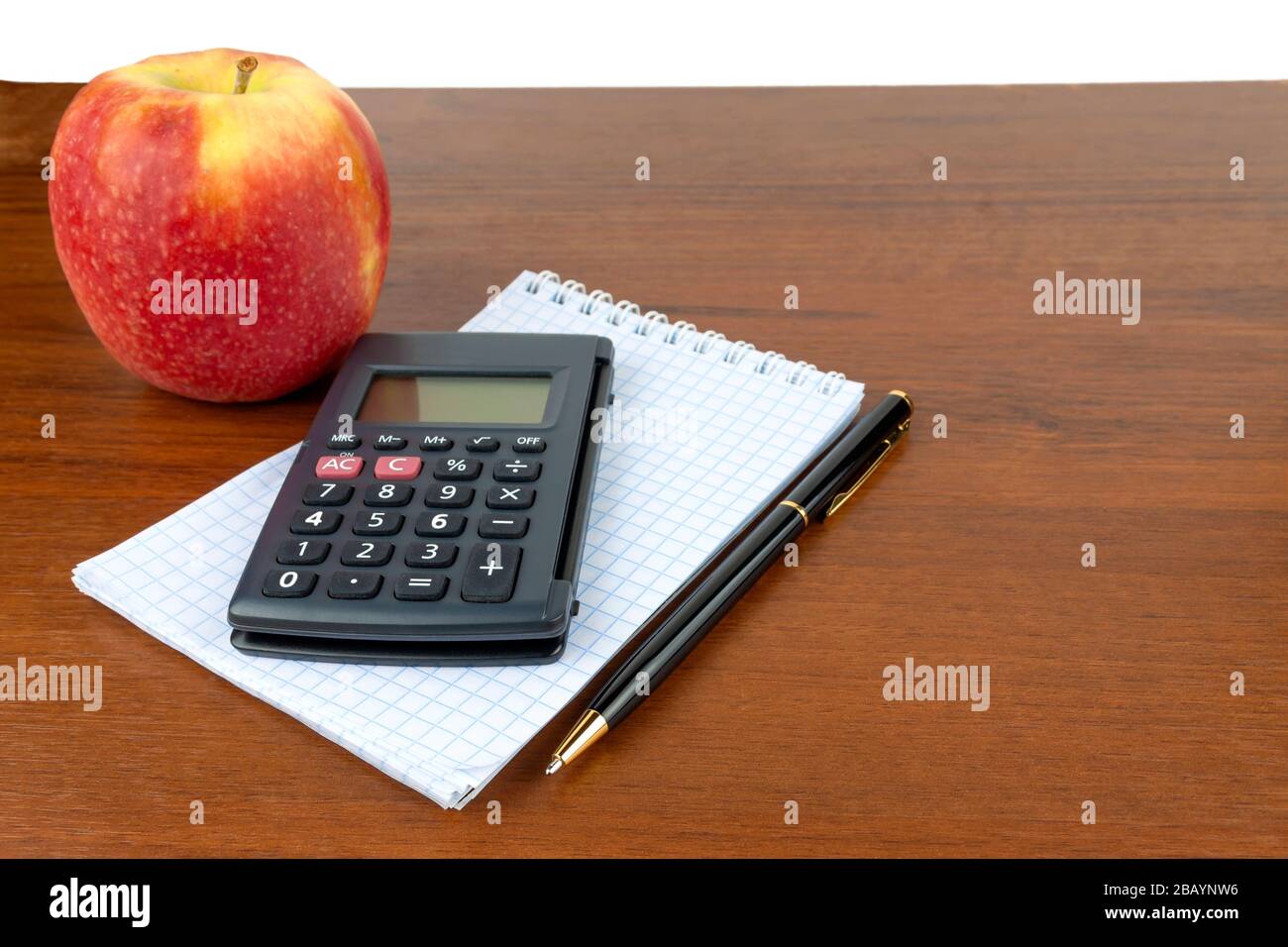 Apple notepad calculator pen lie on the table. Stock Photo