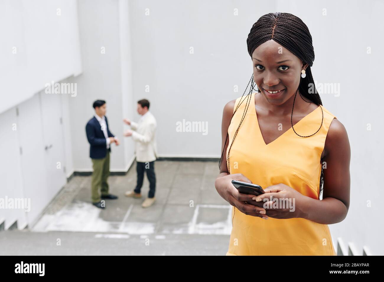 Attractive smiling young Black businesswoman checking notifications on her smartphone Stock Photo